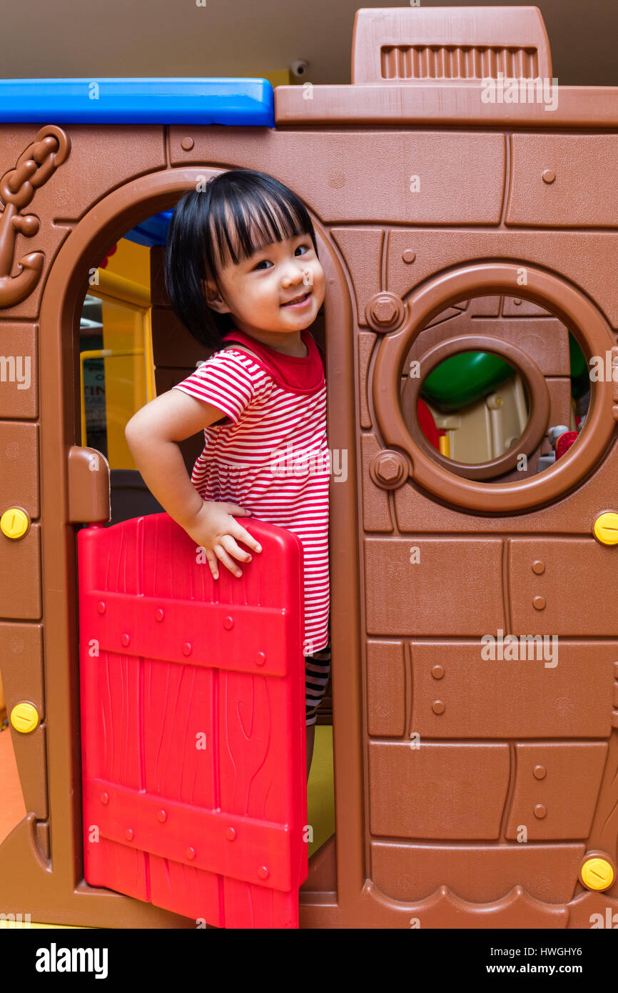 Asian Chinese little girl playing in toy house at indoor playground ...