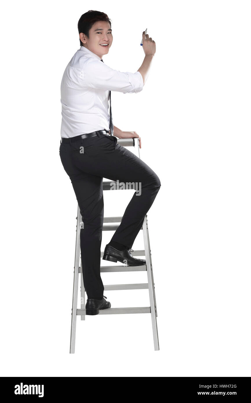 Asian man write something with pen on the ladder isolated over white background Stock Photo