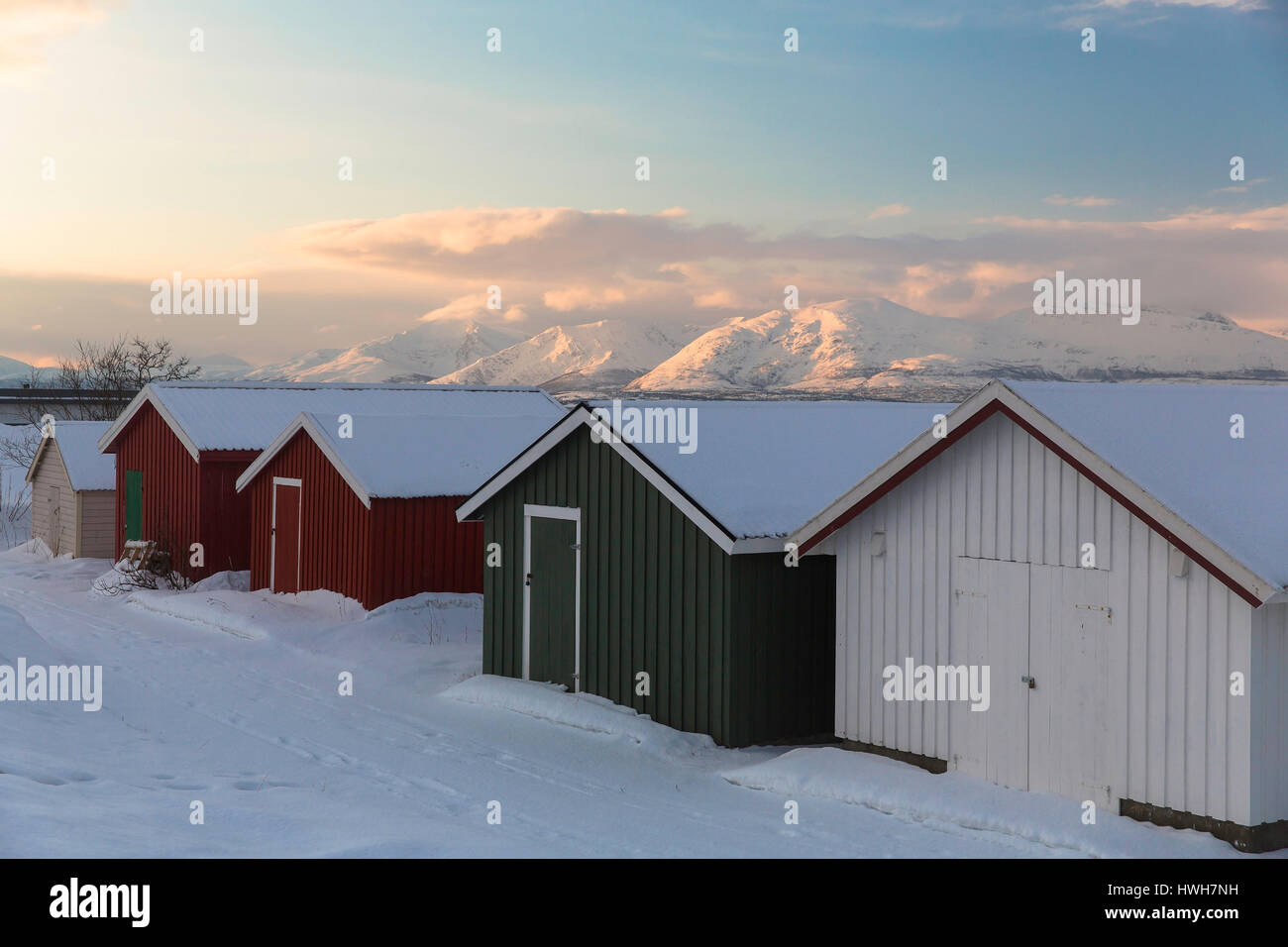 'Boathouses in Troms?, Norway; Troms; Troms?; Troms?; Sandnessund; Malangen, mountains; seasons; winter; tomorrow; weather; clouds; coast; boathouses, Stock Photo