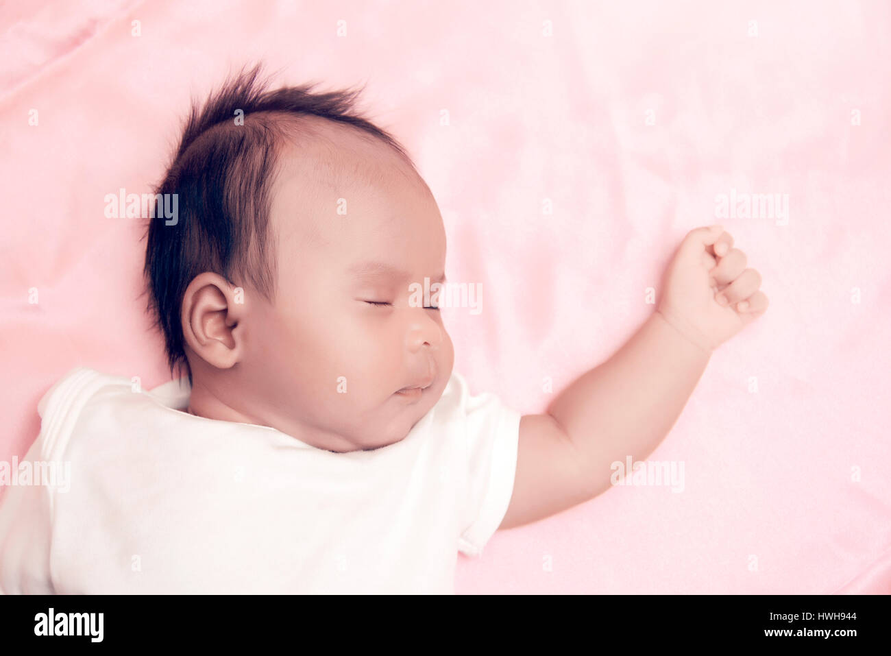 Peaceful baby lying on a bed while sleeping in a bright room over white sheet Stock Photo