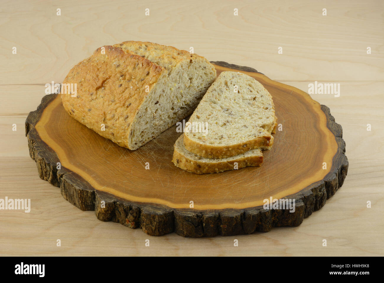 Loaf and slices of nine grain wholegrain bread on wood cutting board Stock Photo