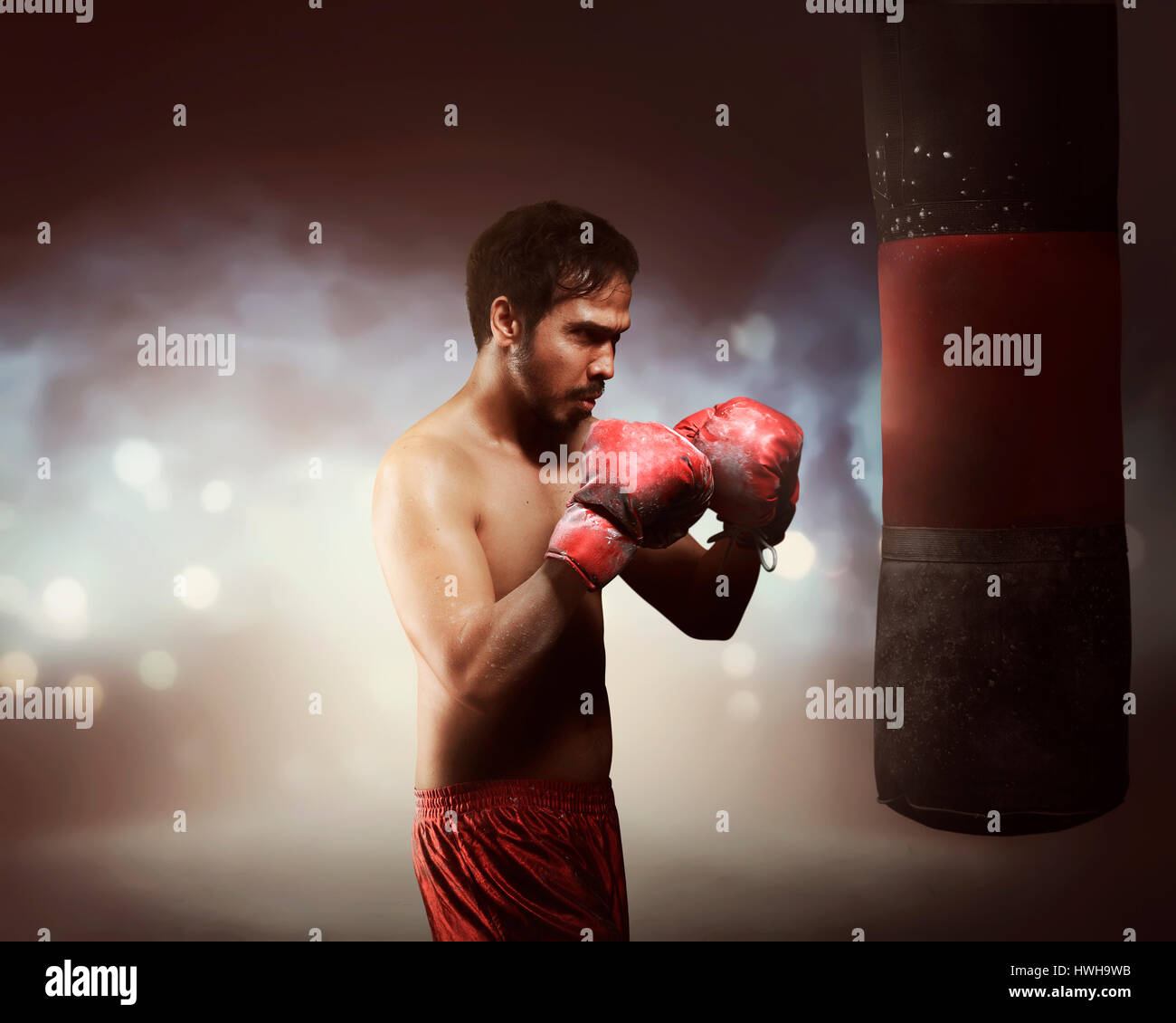 Masculine asian boxer man exercising with punching bag in light flashes  Stock Photo - Alamy