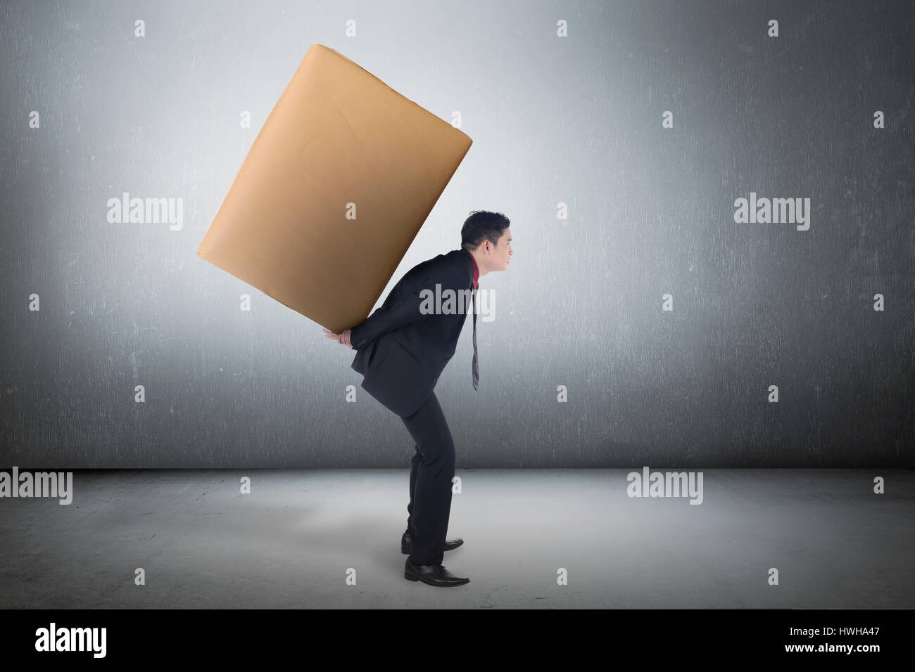 Image of asian business man carrying brown package on his back Stock Photo