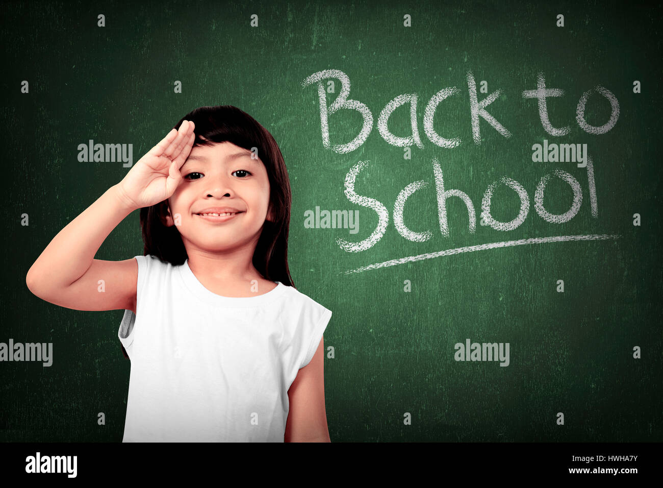 Cheerful smiling little girl on chalkboard background. Looking at camera. Back to school concept Stock Photo