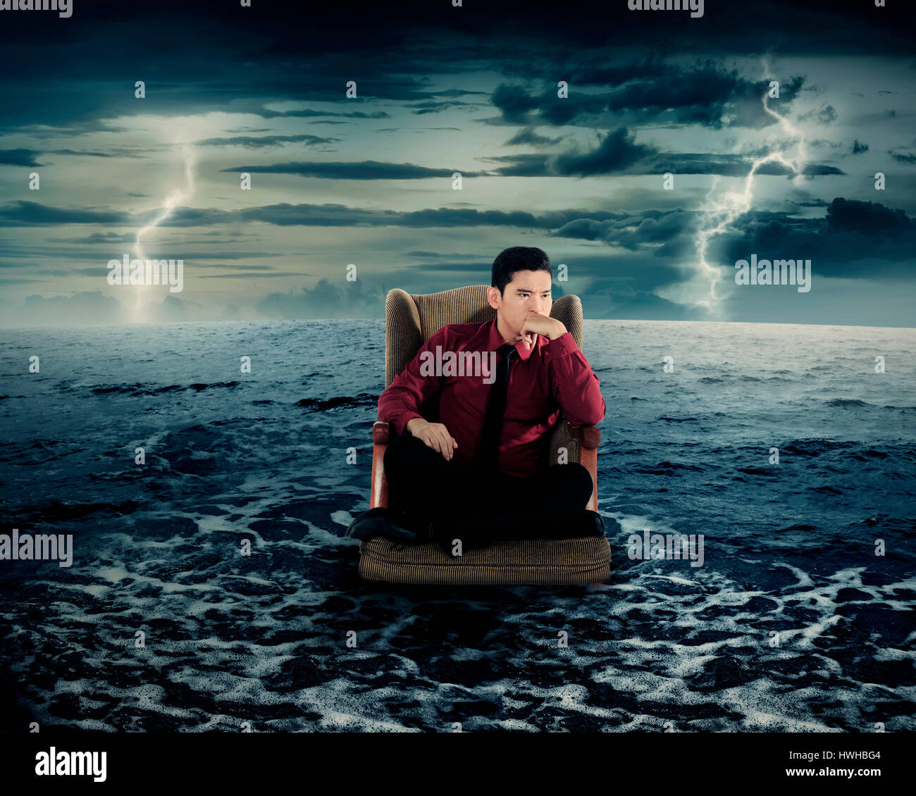 Business man sitting on armchair in the ocean water. Danger concept. Stock Photo