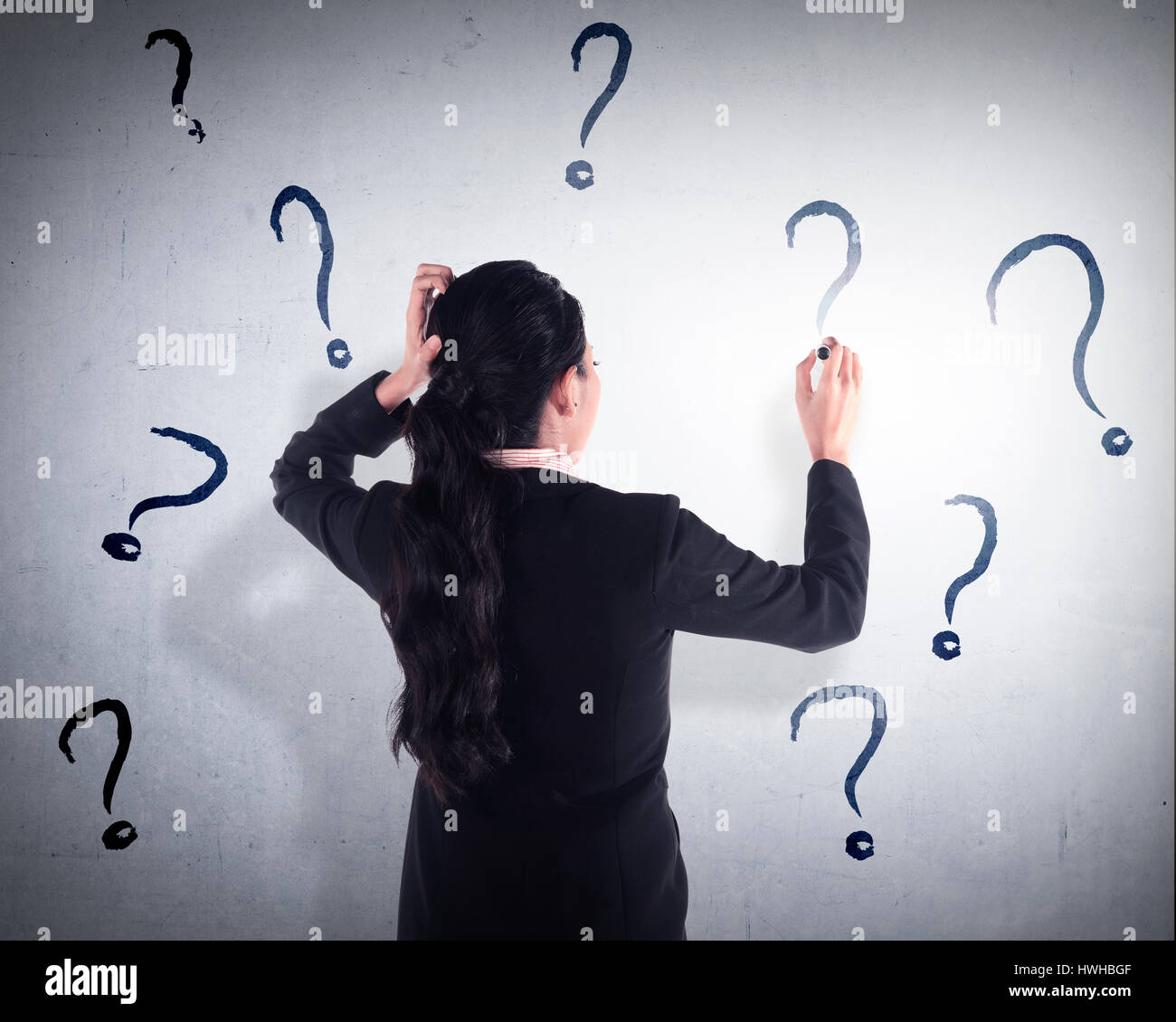 Business woman write question mark on the wall. She dont know what to write Stock Photo