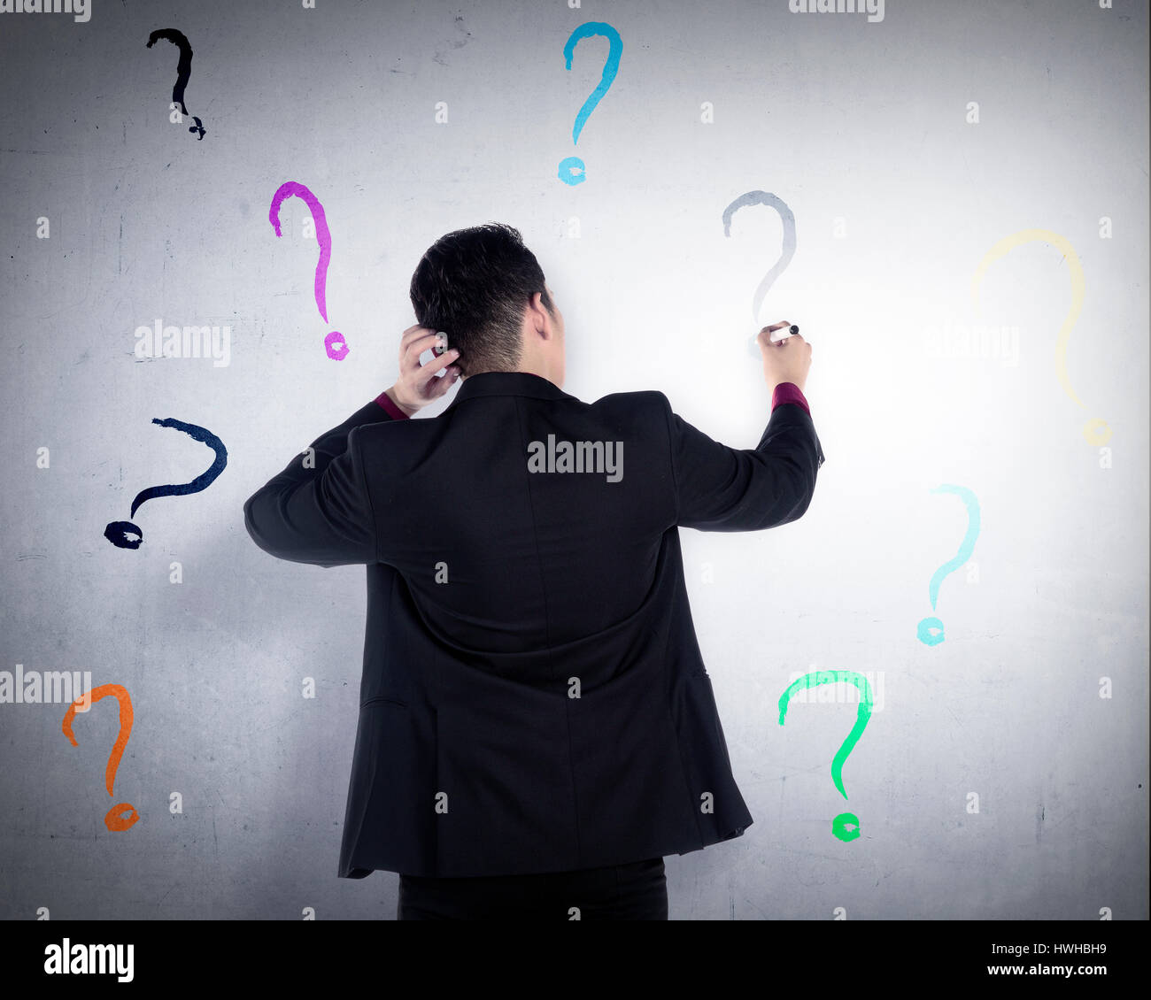 Business man write question mark on the wall. He dont know what to write Stock Photo