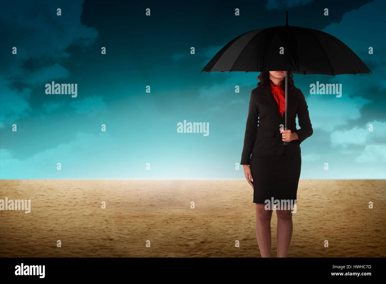 Business person holding umbrella standing on the desert Stock Photo