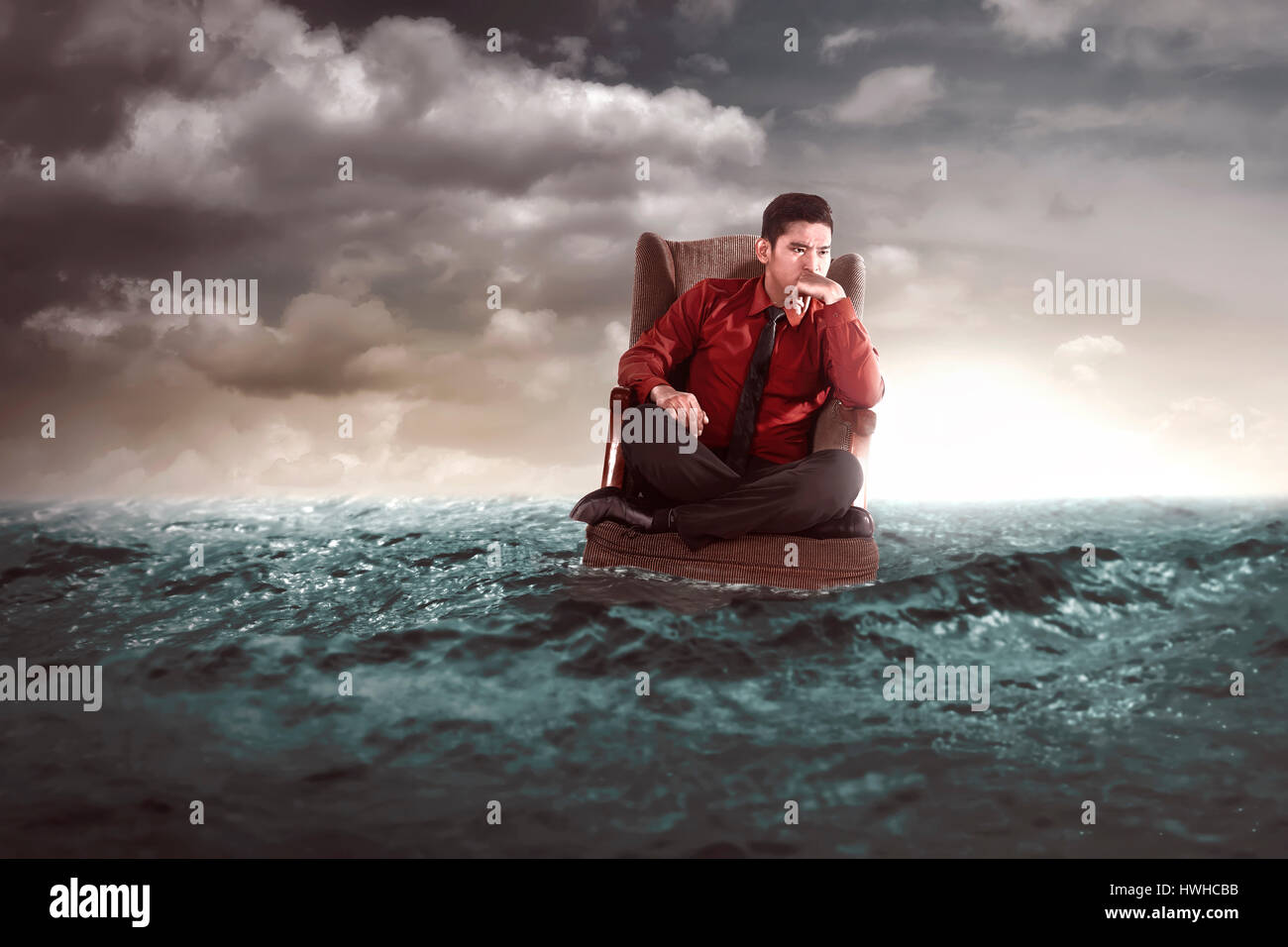 Businessman sitting on an armchair in the middle of the sea. He thinking something Stock Photo