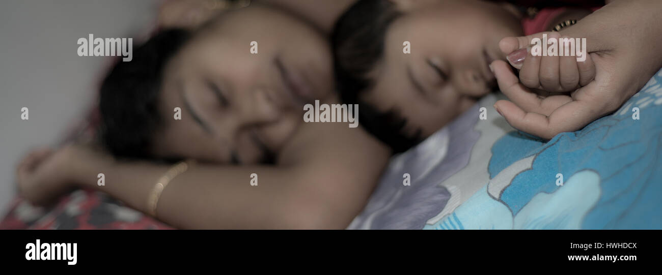 Mother holding her baby's hands while sleeping Stock Photo