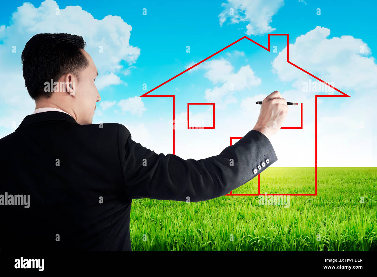 Business man drawing house on the meadow with blue sky background Stock Photo