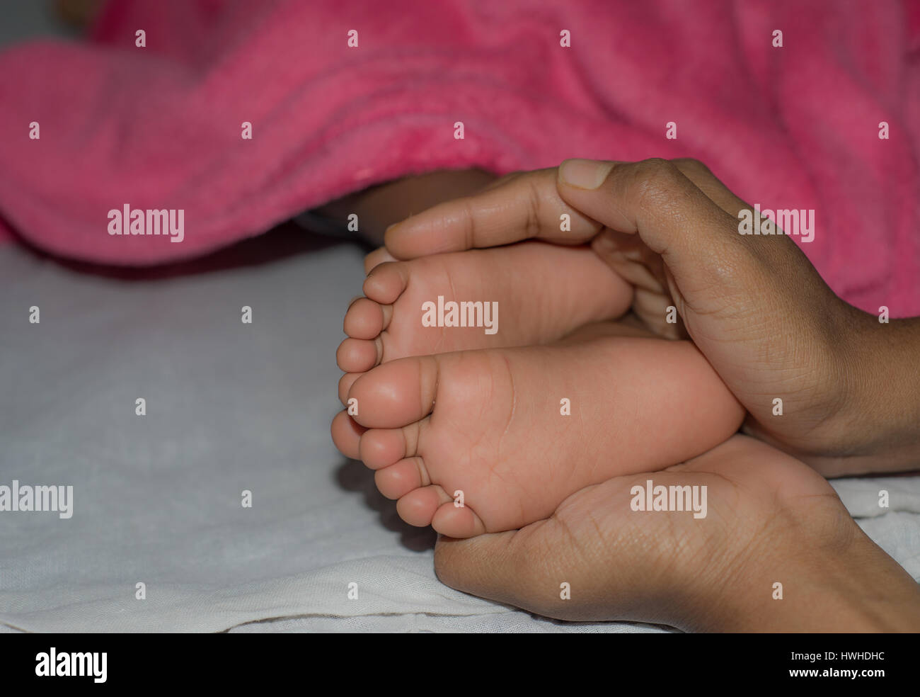 Mother holding her baby's feet while sleeping Stock Photo