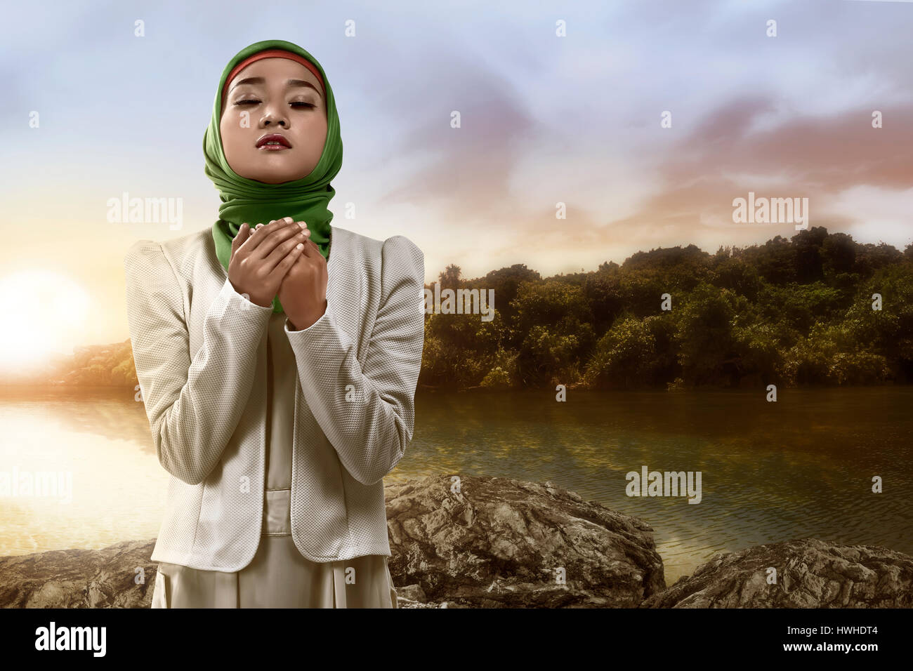 Young muslim woman praying standing on the rock at the lake Stock Photo ...