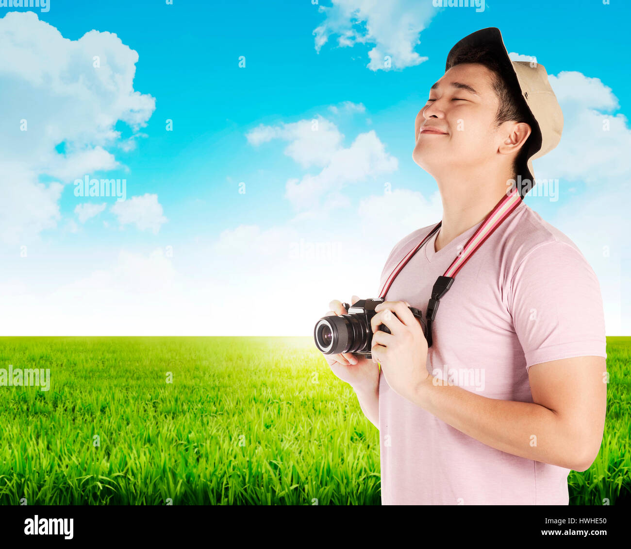 Asian tourist take photo on green meadow. Summer holiday concept Stock Photo