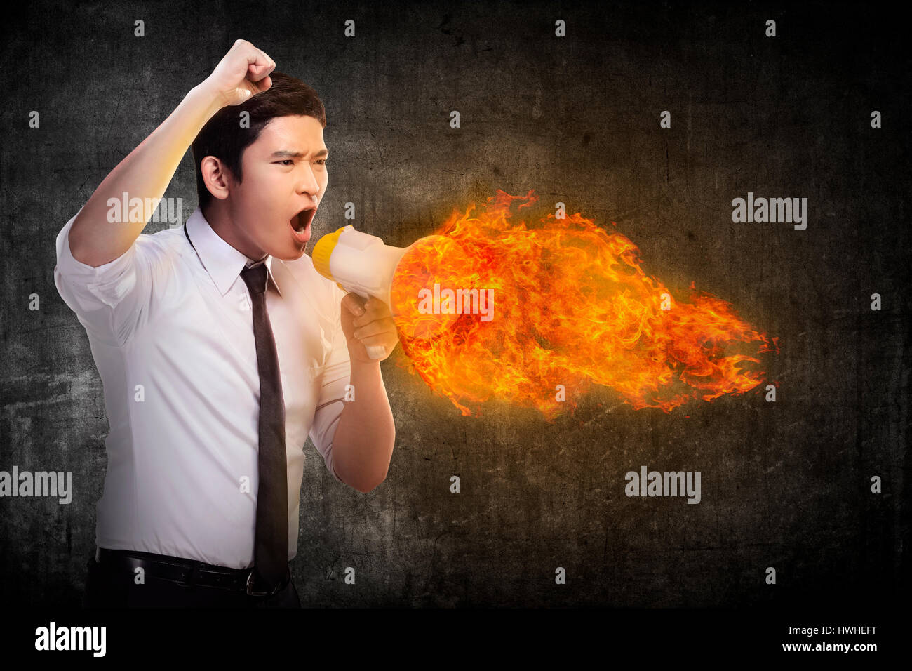 Business man holding megaphone in fire and shouting with furious Stock Photo