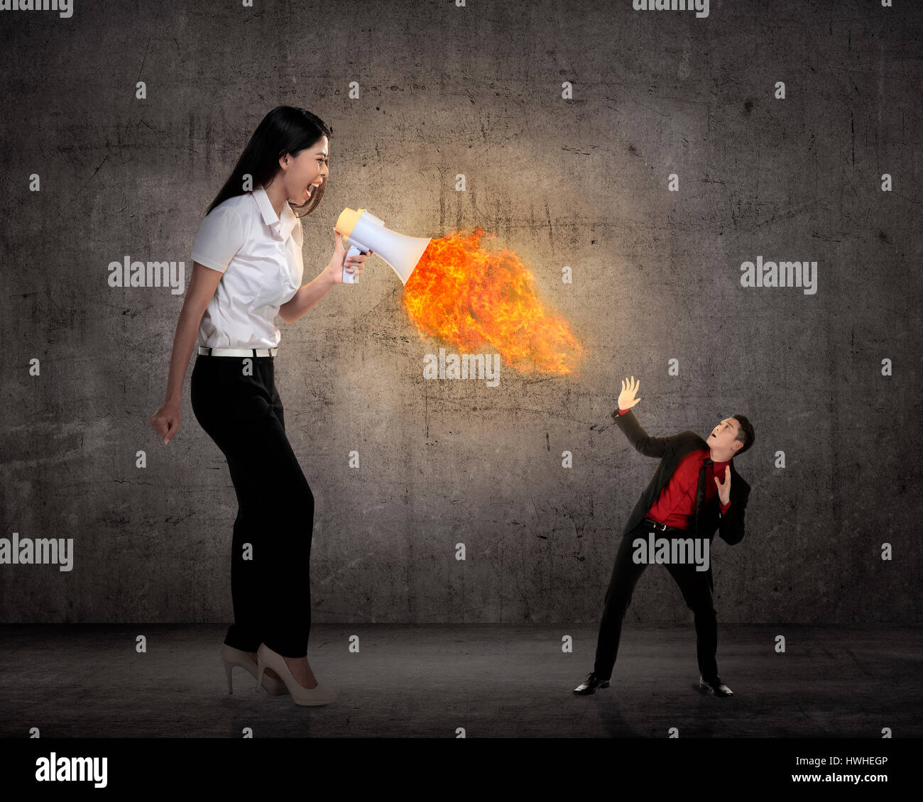 Big boss yelling to her employee with megaphone on fire. Work pressure concept Stock Photo