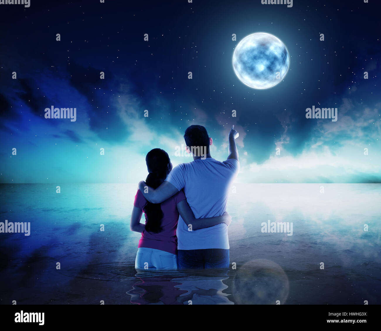 Young couple ponting moon at night time in the sea Stock Photo - Alamy