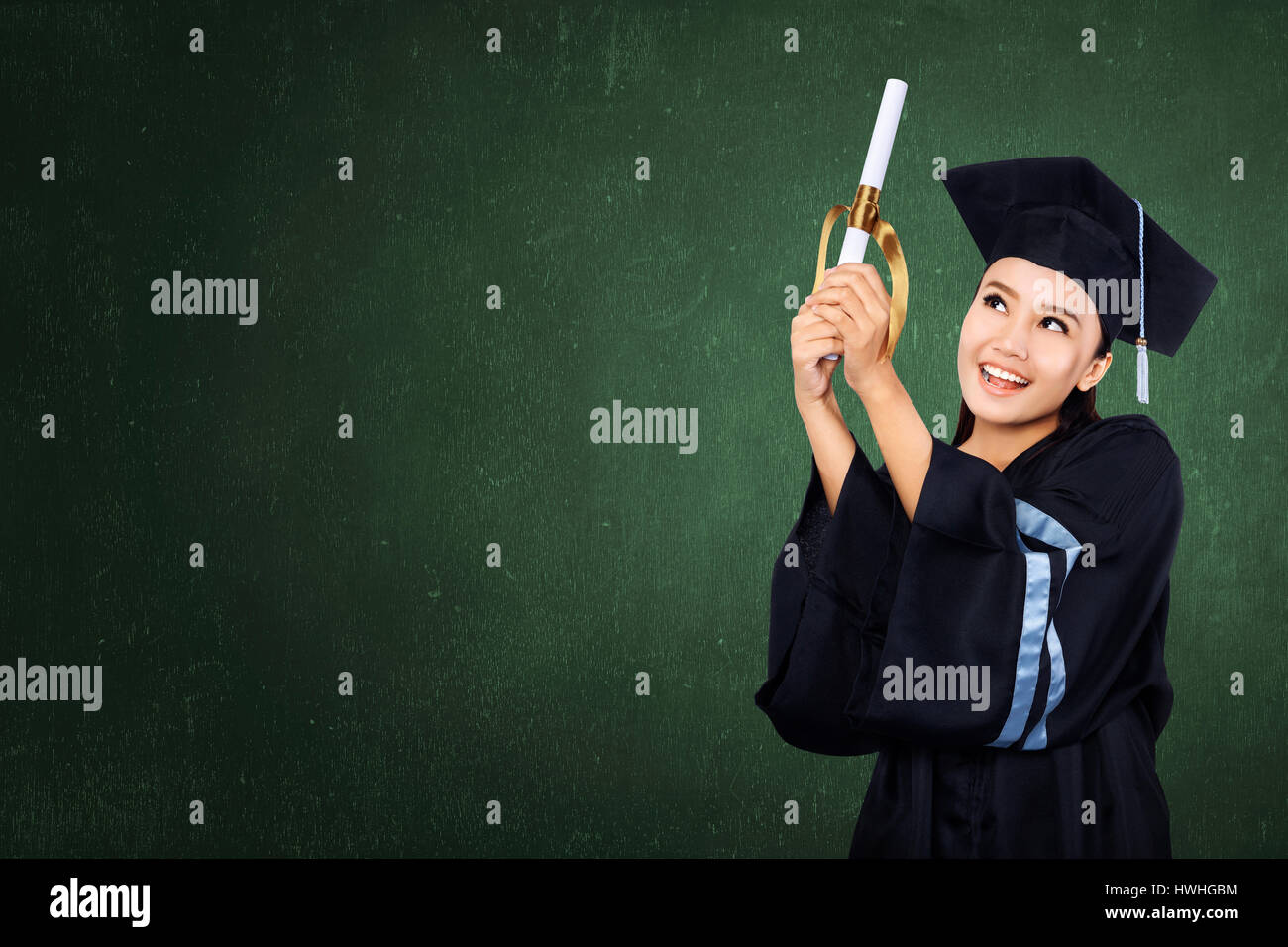 Happy graduated student girl with scroll on green chalkboard background Stock Photo
