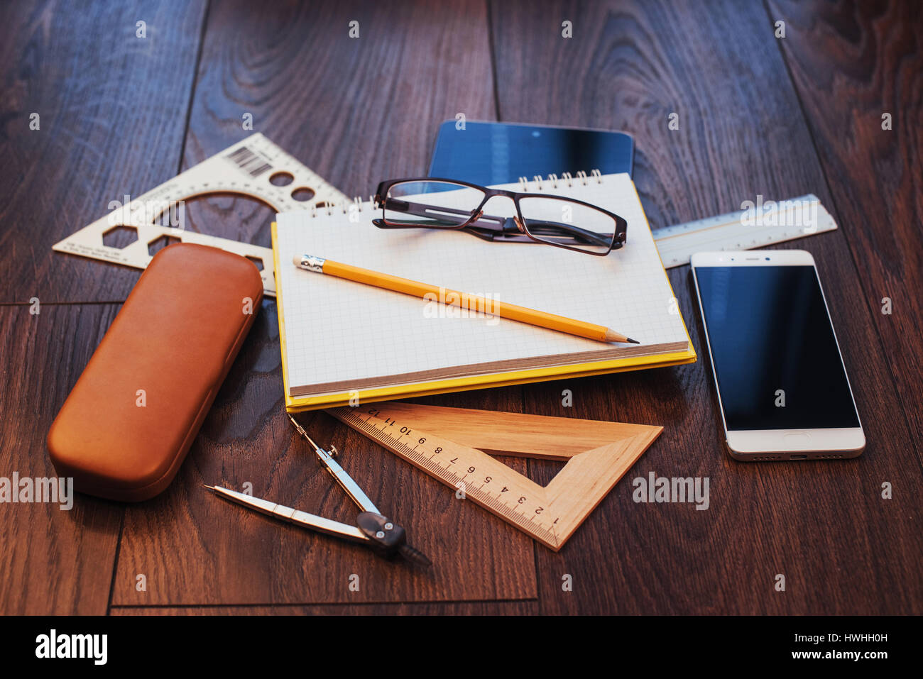 Top view of notebook, stationery, drawing tools and a few glasses