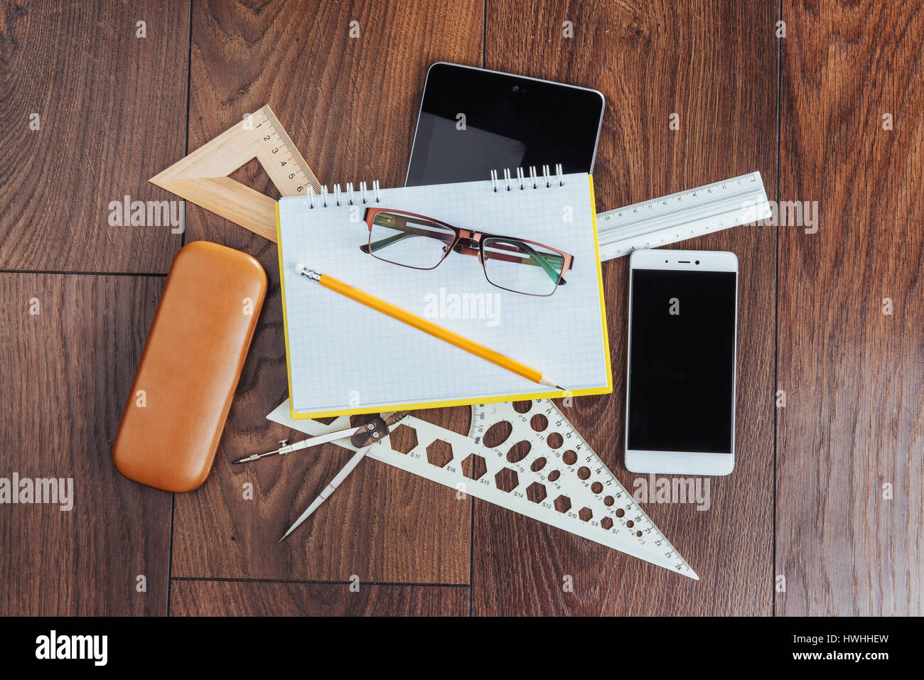 Top view of notebook, stationery, drawing tools and a few glasses