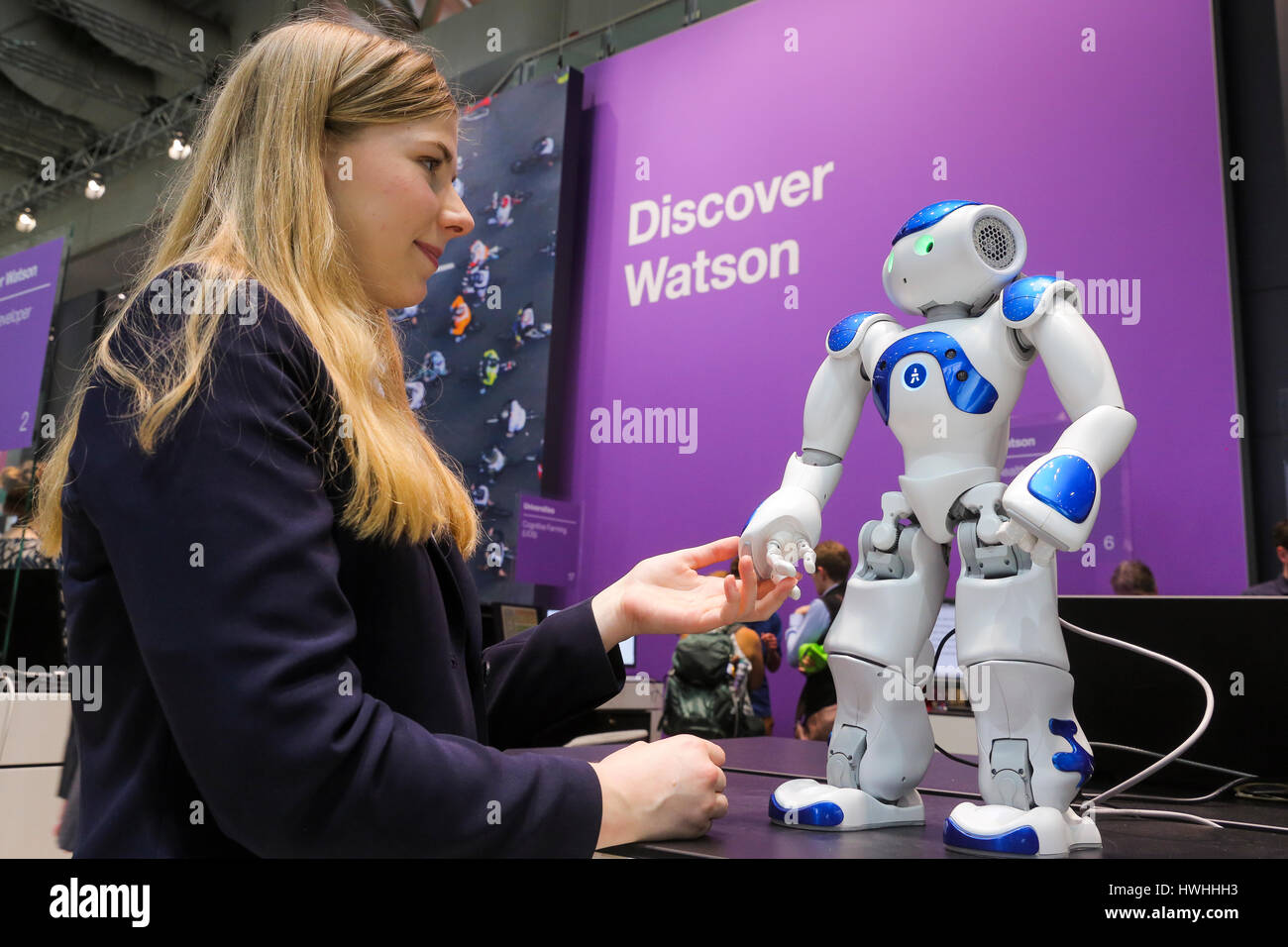 Hannover, Germany, 20th March 2017 - CeBIT digital technology trade fair. A stand hostess touches a humanoid NAO Watson robot at the IBM stand Stock Photo
