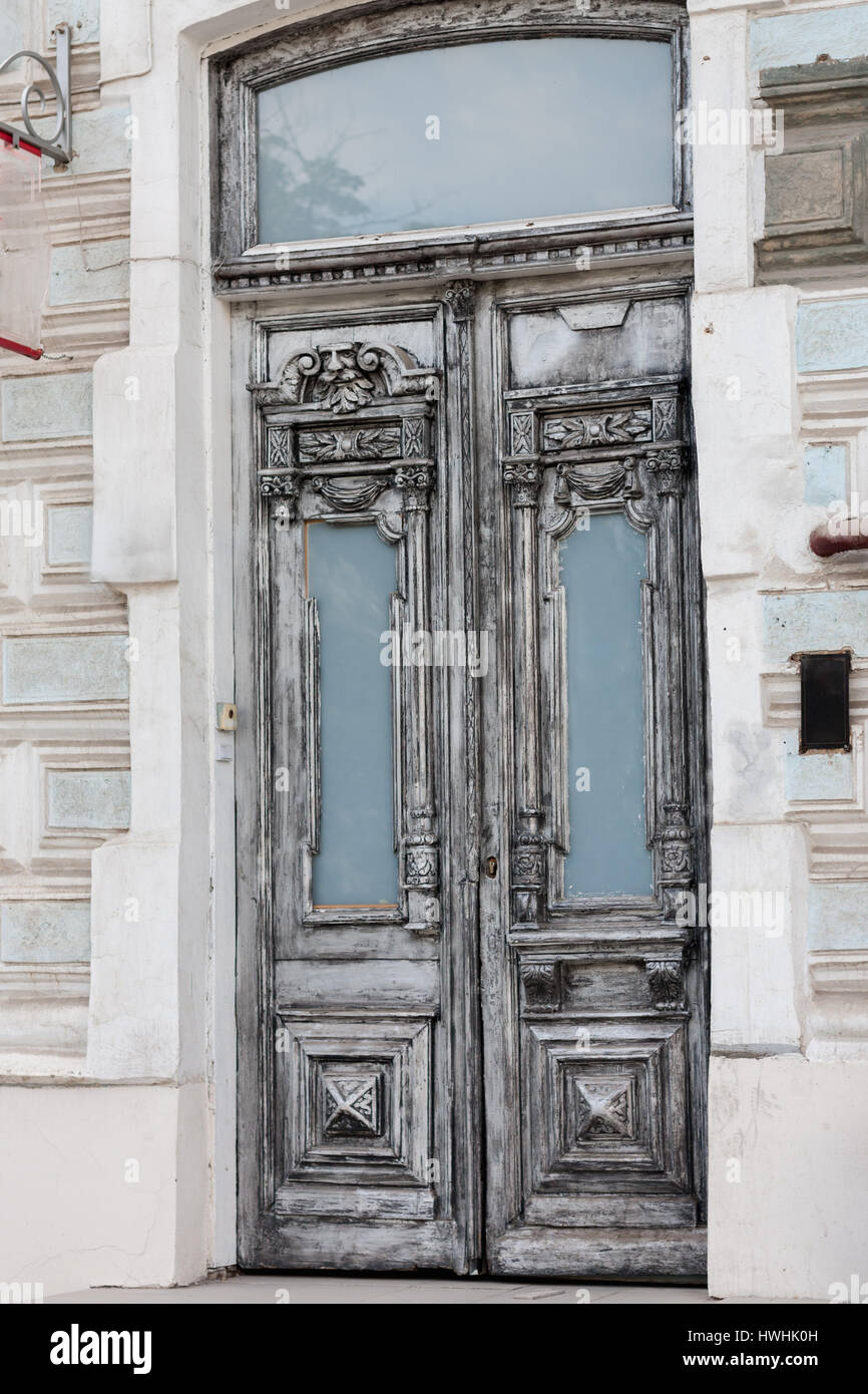 Olde grey vintage double-leaf door made of carved decorations painted in white wood framed with biege stones in Rostov-on-Don Russia Stock Photo