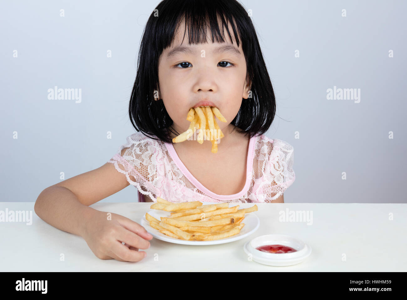 Asian Chinese little girl Refusing Eating French fries with clean isolated background. Stock Photo