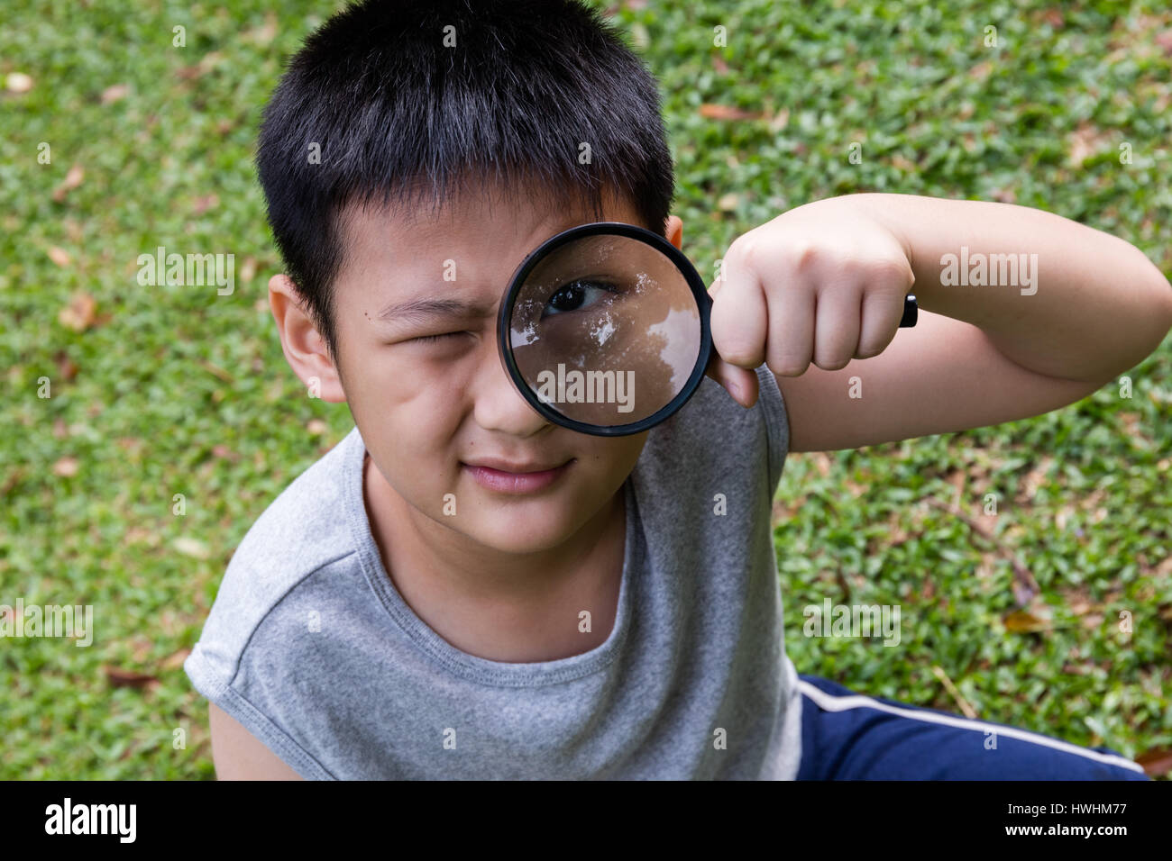 Happy Asian Chinese little boy looking through magnifying glass at