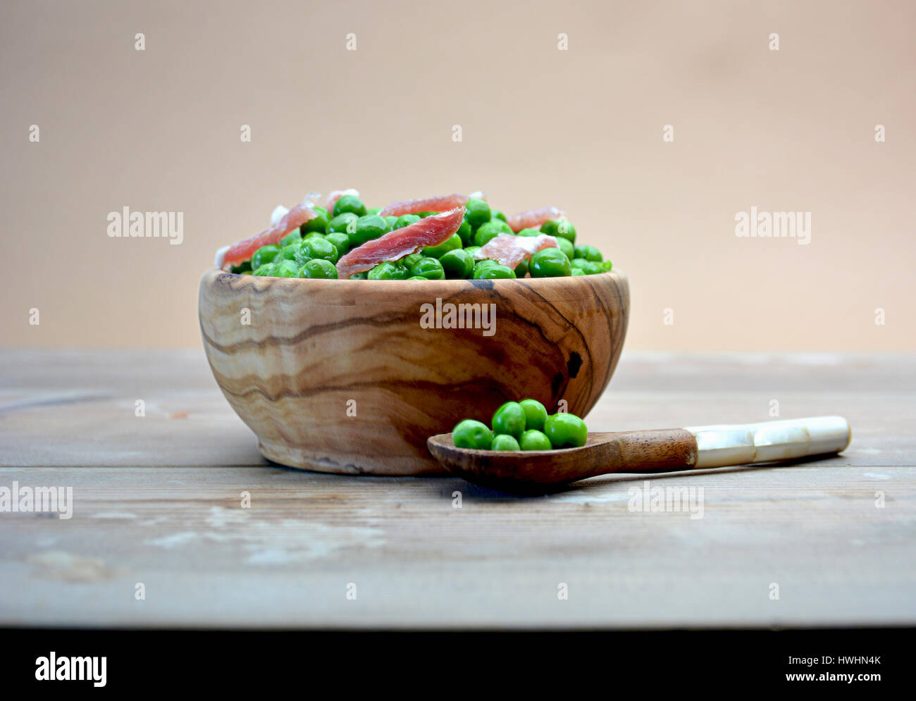 DISH OF WOOD FULL OF PEAS WITH HAM ON TABLE RUSTIC Stock Photo