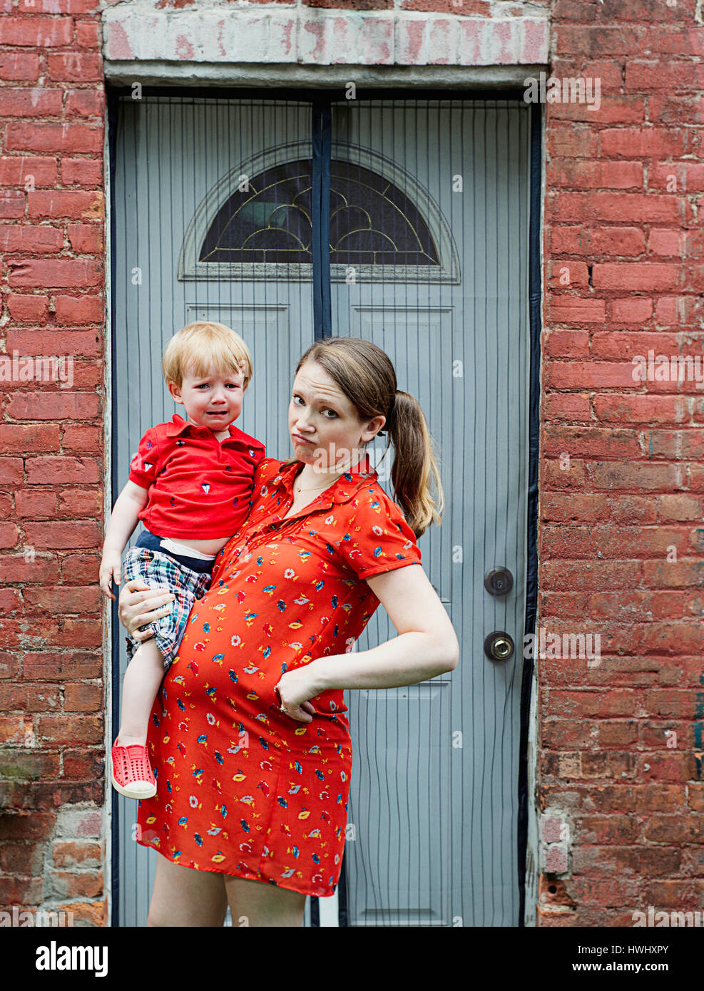 A pregnant woman holding her crying child Stock Photo