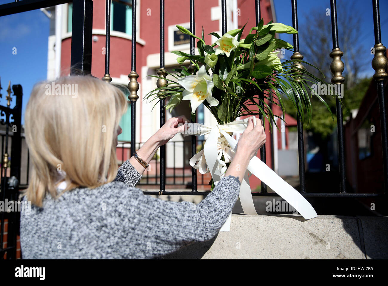 Constituency staff of Belfast West MLA Alex Maskey tie lilies to the gates of Connolly House, Andersonstown, Belfast, after the death of Northern Ireland's former deputy first minister and ex-IRA commander Martin McGuinness aged 66. Stock Photo