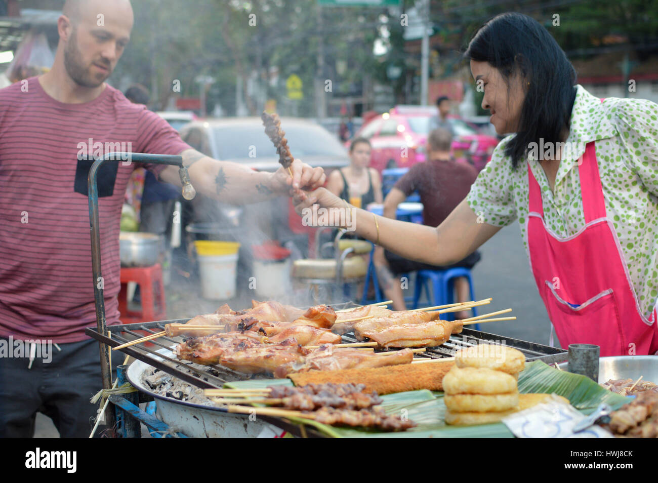 Bangkok, Thailand - February 19, 2017: Tourist buys the street food from the vendor at the Khaosan Road in Bangkok Thailand Stock Photo