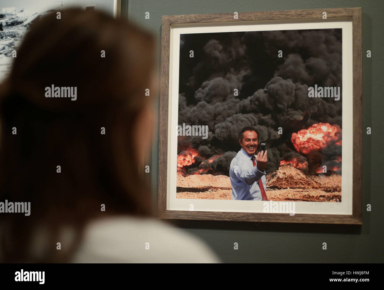 A member of the museum staff looking at a photomontage entitled Photo Op, 2007 - depicting former Prime Minister Tony Blair taking a selfie in front of a huge explosion, by artists Peter Kennard and Cat Phillipps - during a press view of the People Power: Fighting for Peace exhibition at the Imperial War Museum in London. Stock Photo