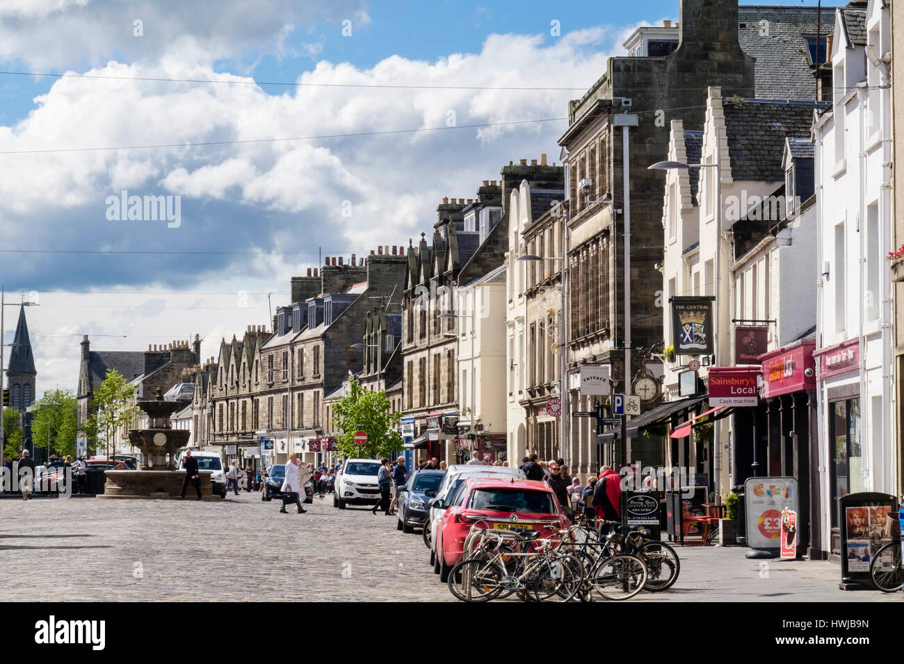 Street scene with cars parked on road outside small shops in town centre. Market Street, Royal Burgh St Andrews, Fife, Scotland, UK, Britain Stock Photo