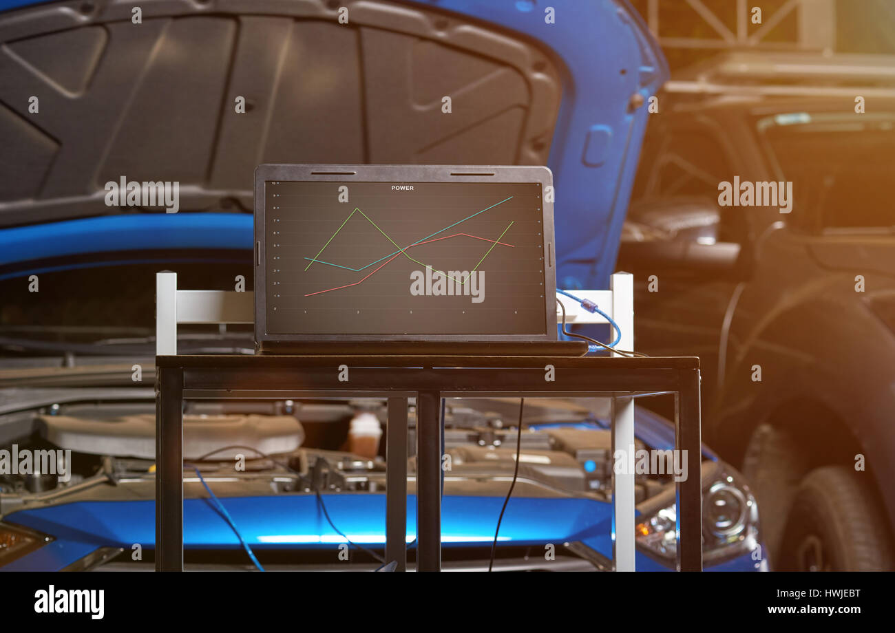 Car garage diagnostic station with computer table on blue blurred vehicle background Stock Photo