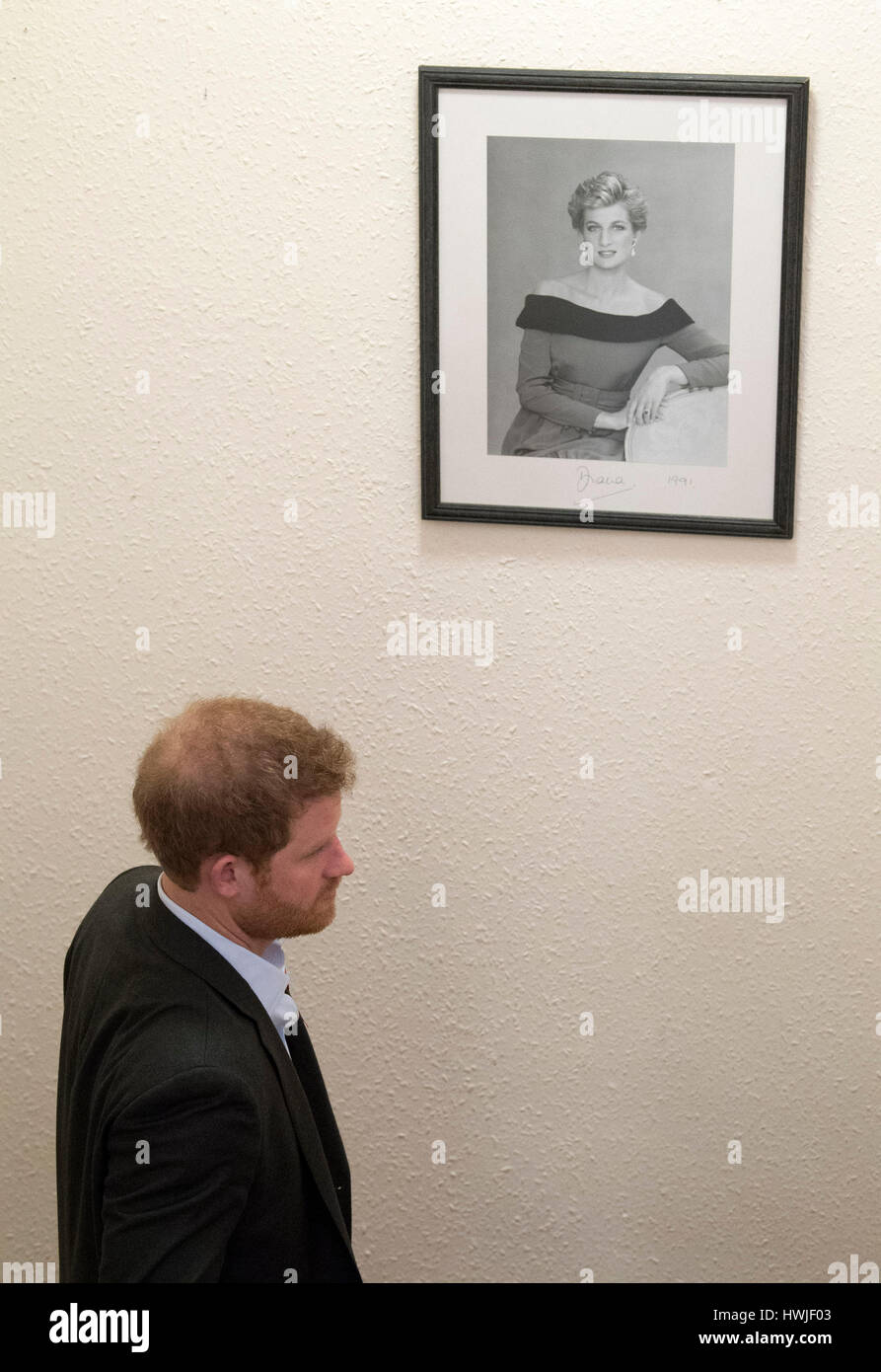 Prince Harry walks past a photograph of his mother, Diana, Princess of