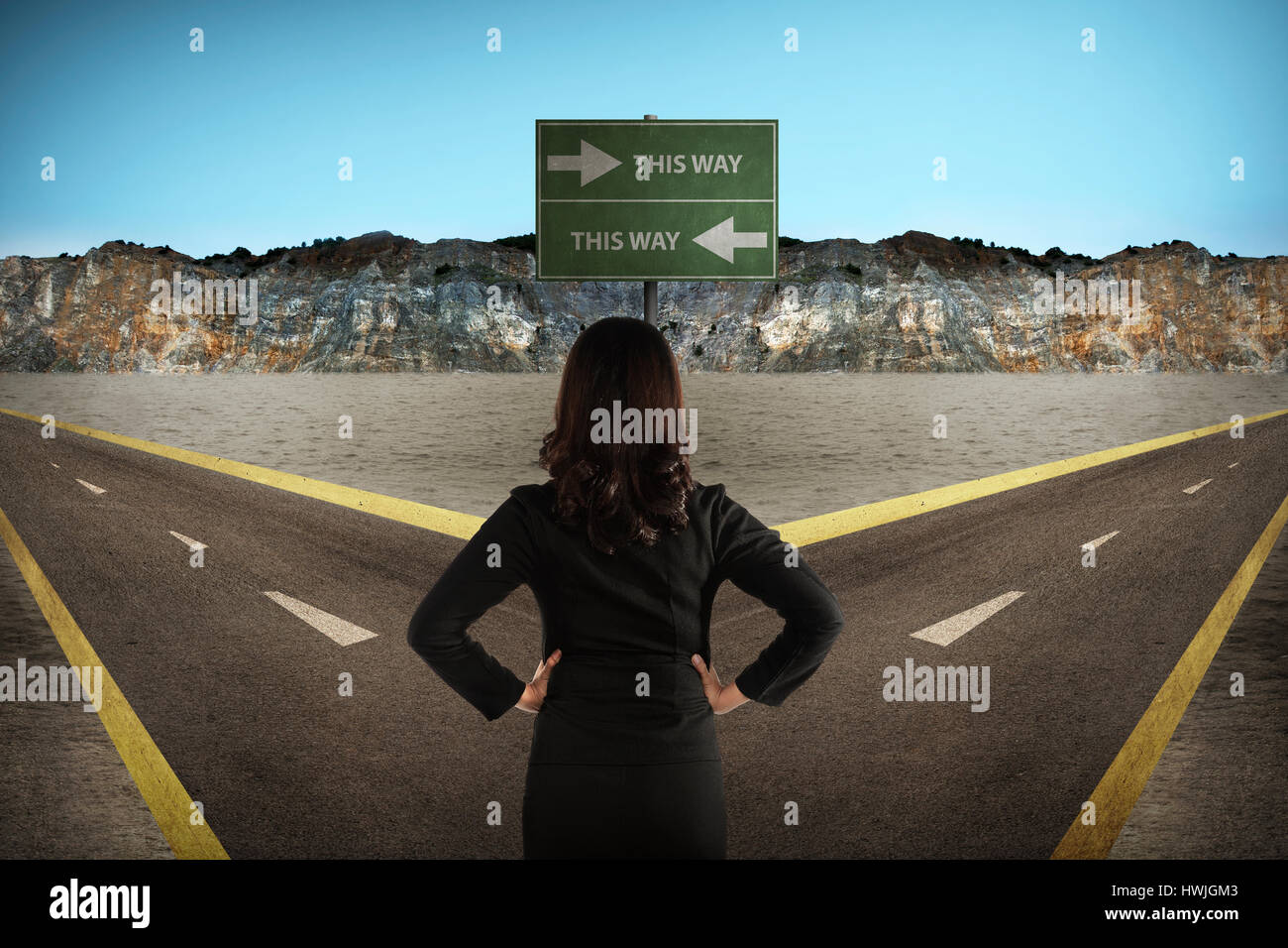 Asian woman standing in the middle of cross road thinking about direction Stock Photo