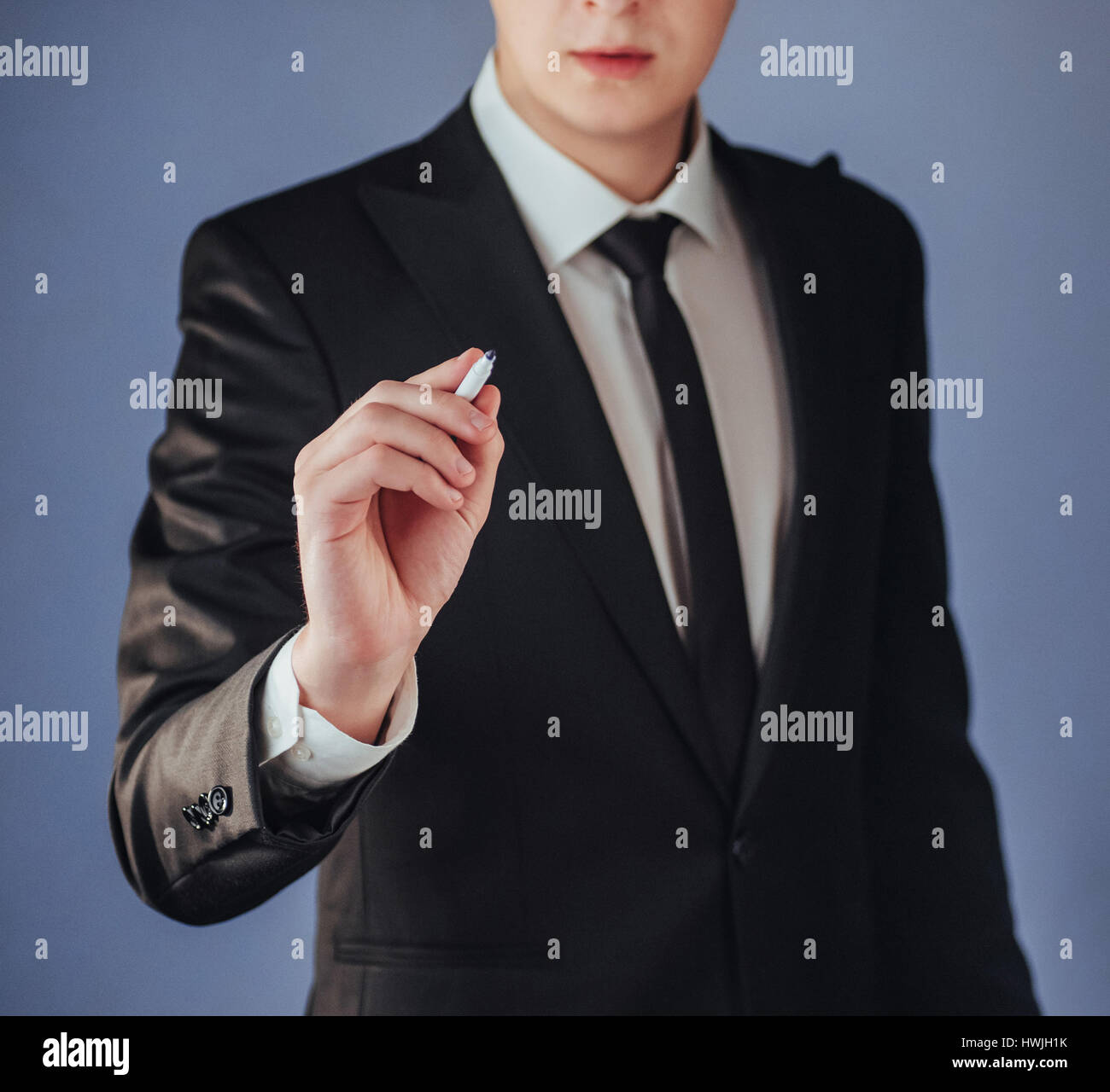 businessman in black suit writing something on glass board with marker ...