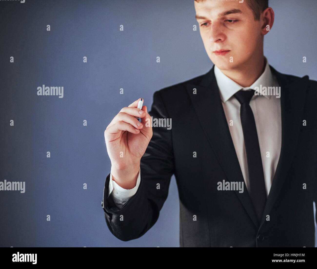 businessman in black suit writing something on glass board with marker ...