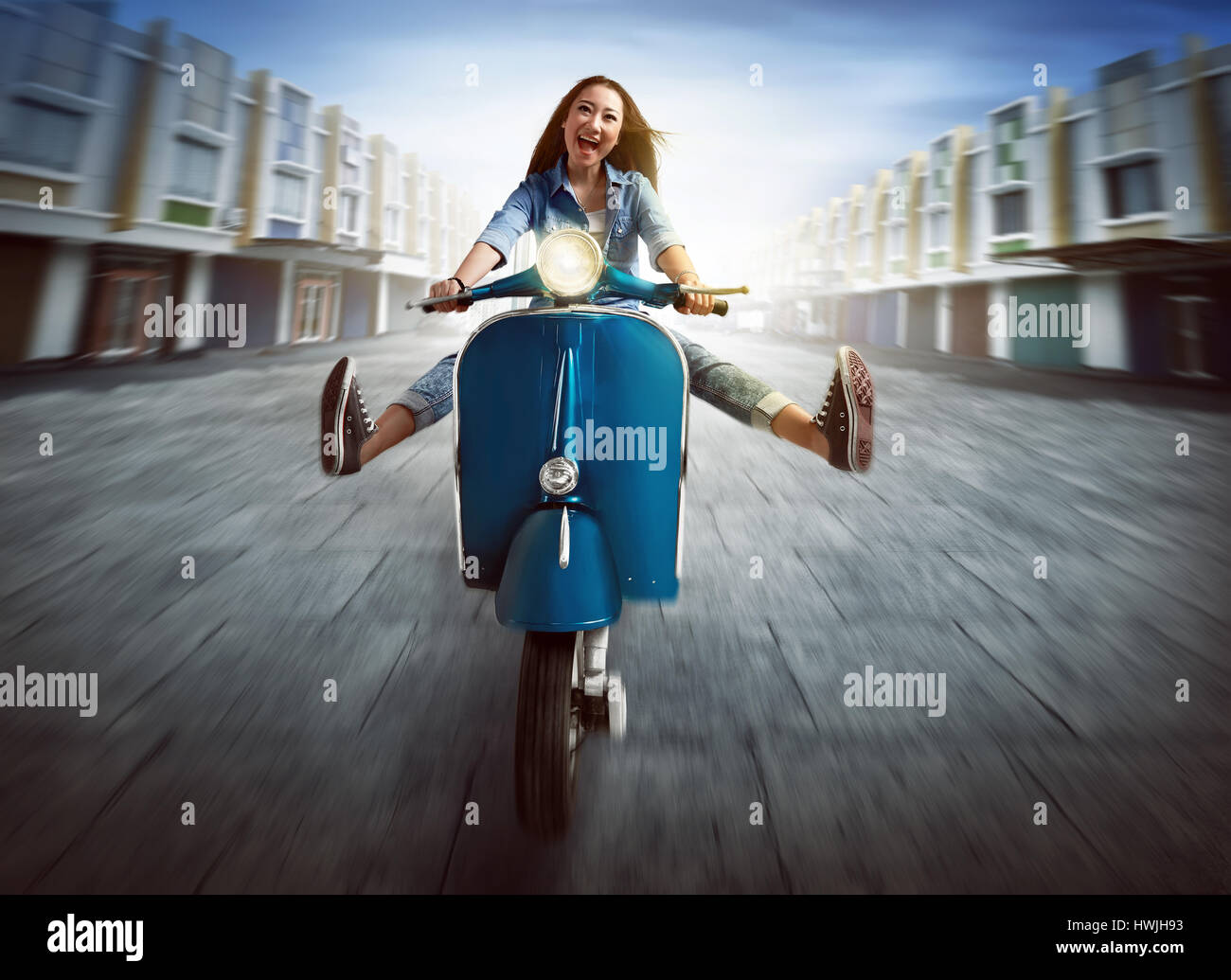 Beautiful young asian woman riding a motorcycle and lift both legs amid the city Stock Photo