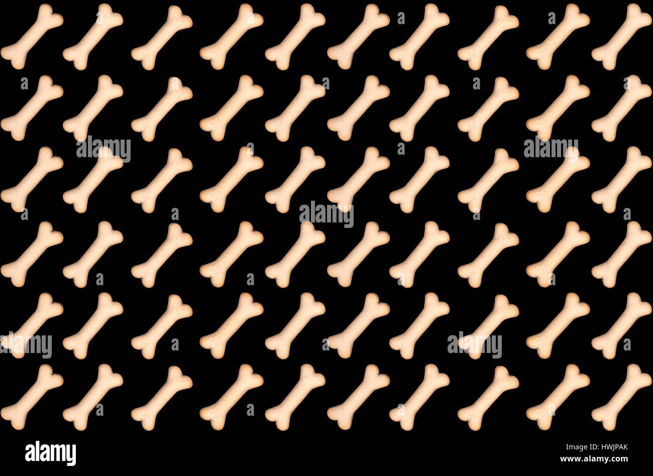 A seamless pattern of dog biscuits, in the shape of bones, isolated on black background. Stock Photo