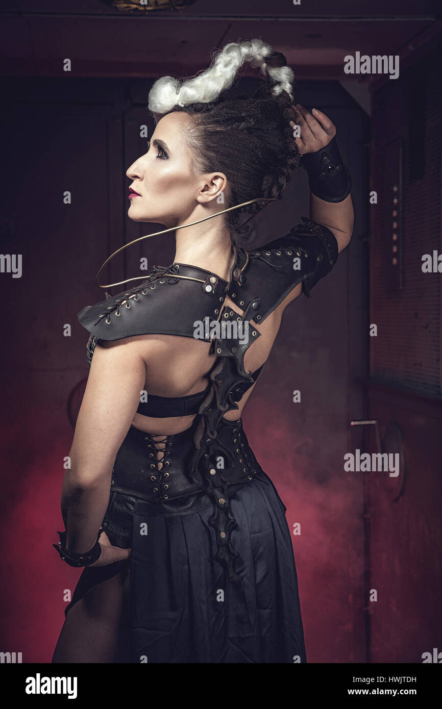 Beautiful warrior woman. Fantasy fighter. Princess or queen in leather corset ready for war. Red light and white weapon. Stock Photo