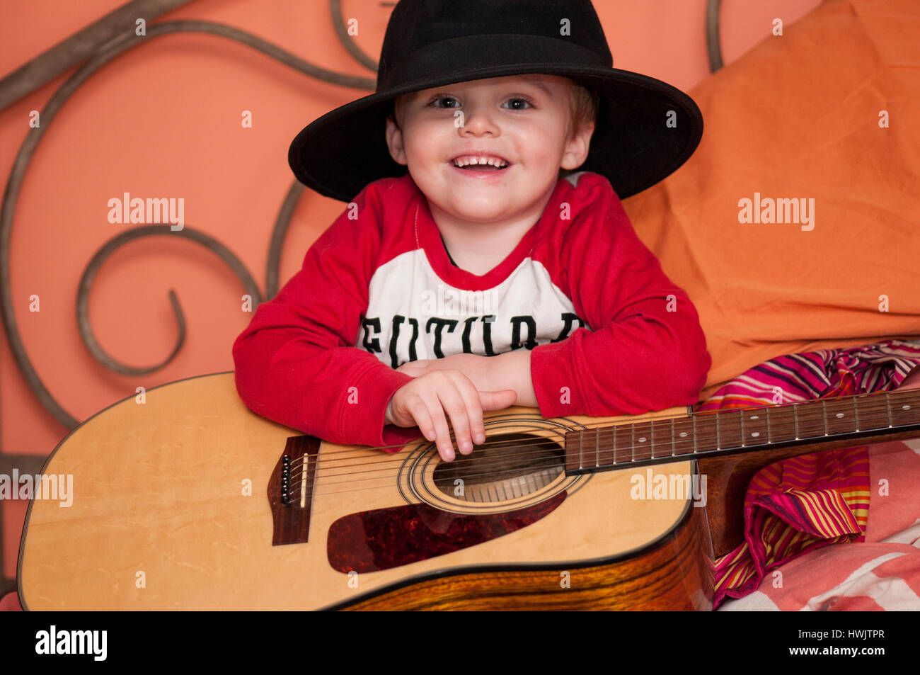 2-3 YEAR OLD CAUCASIAN MALE WITH HAT ON HODING A GUITAR. Stock Photo