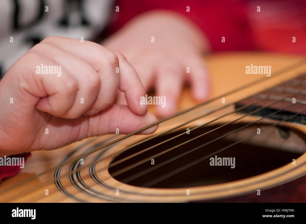 A 3 YEAR OLD CAUCASIAN BOY STRUMS A GUITAR. Stock Photo