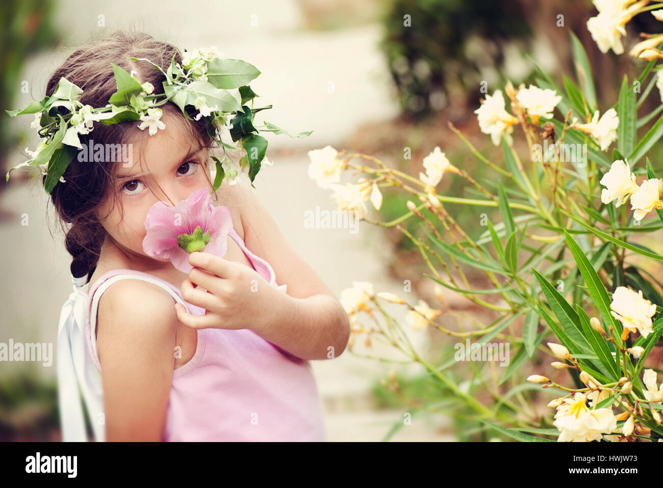 Little girl with flower crown smelling flower Stock Photo