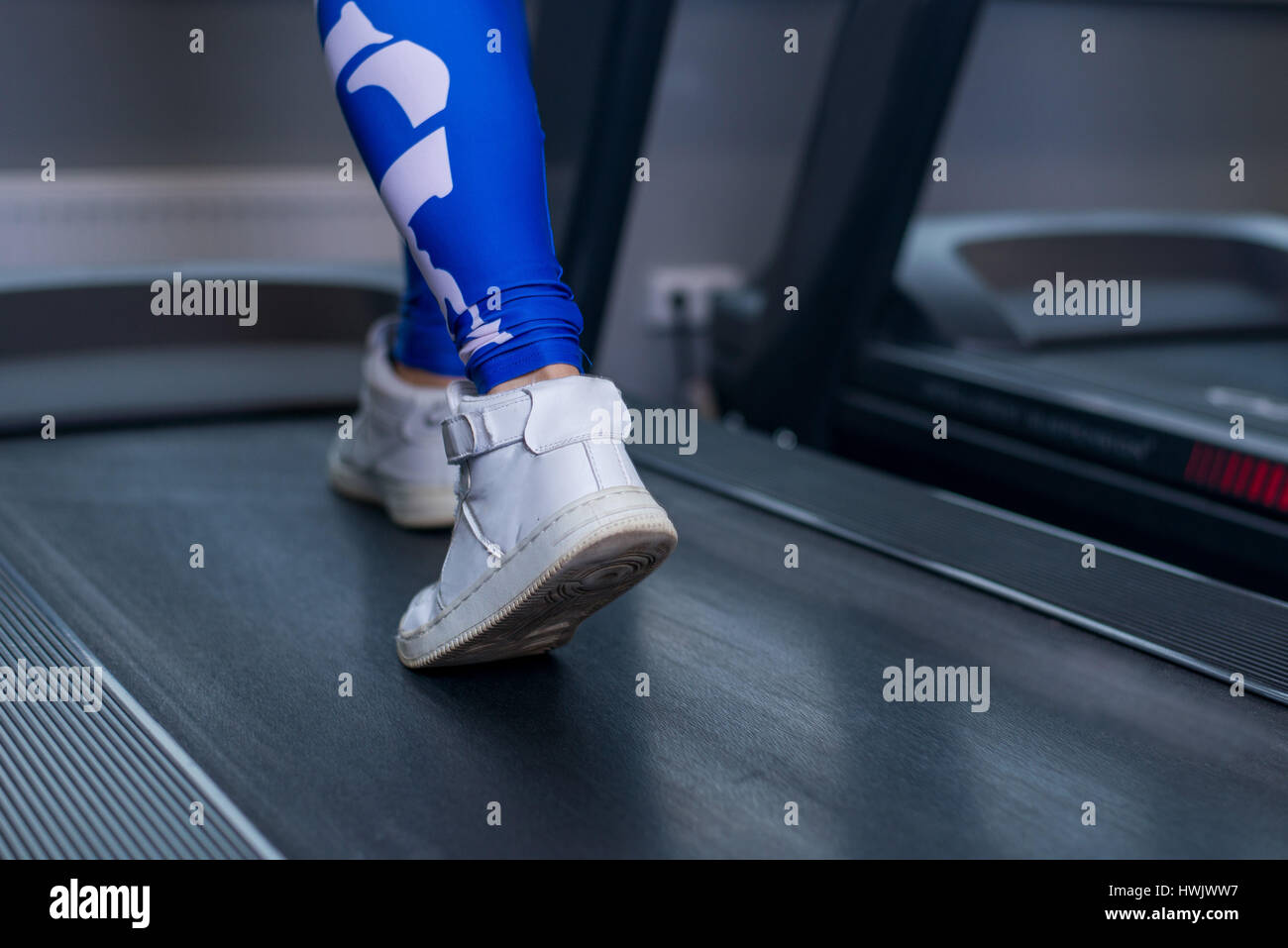 Female muscular legs on treadmill in sport gym. Concept for exercising, fitness and healthy lifestyle Stock Photo