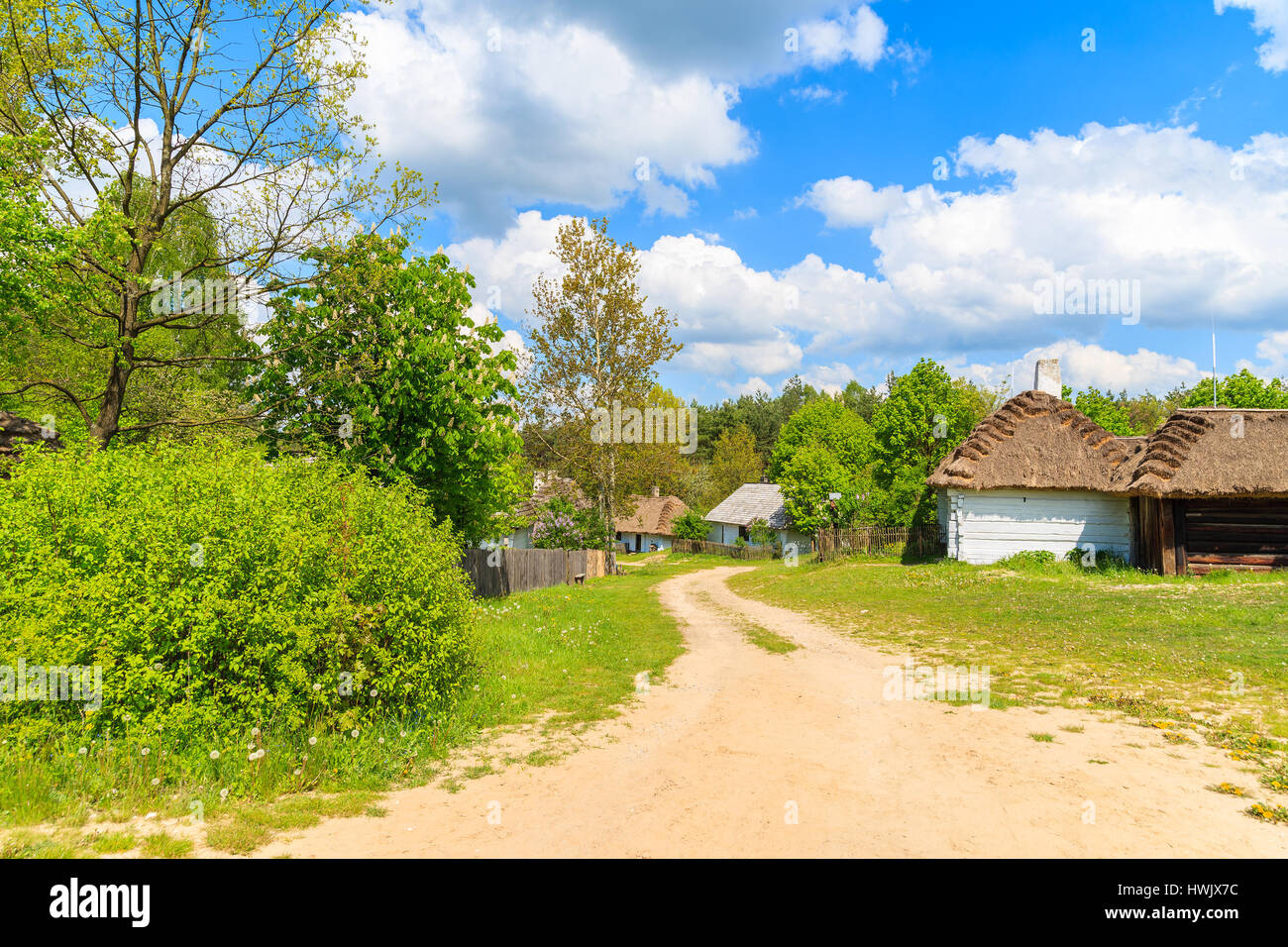 Rural road to Tokarnia village with straw roof houses on sunny spring day, Poland Stock Photo