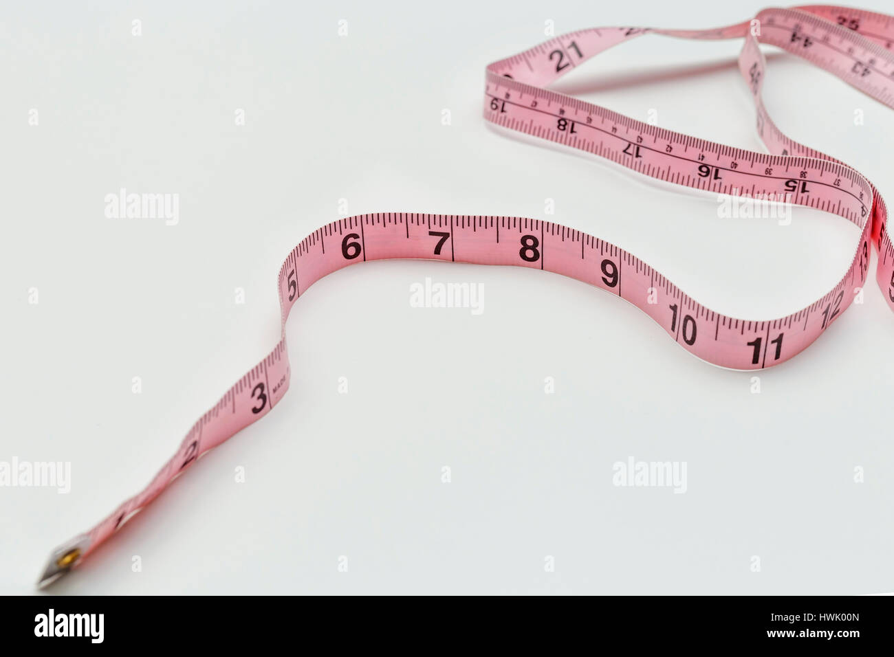 Unfolded white tape measure, White measuring tape isolated on pink