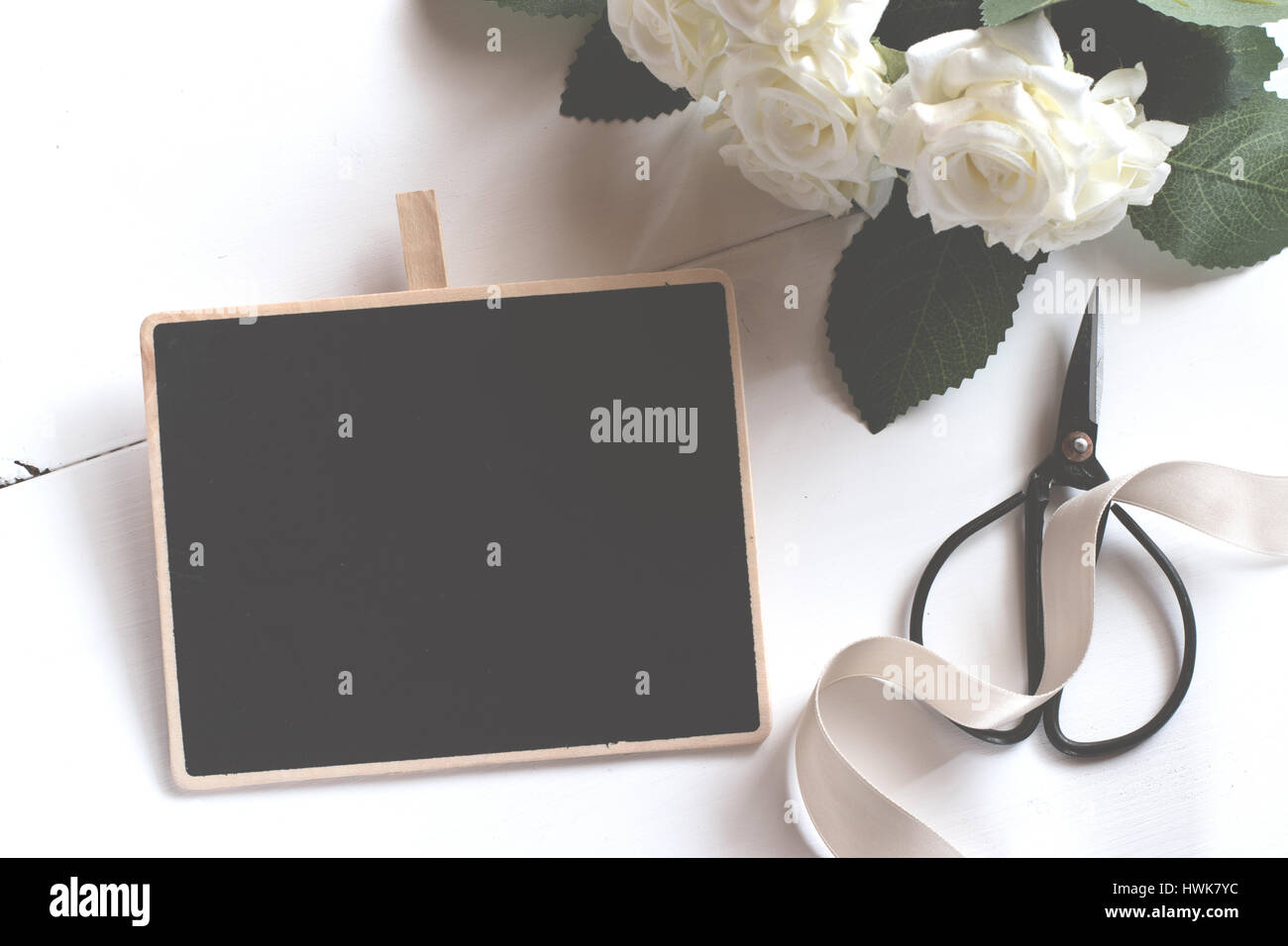 Blank chalkboard with flower bouquet on wooden table. Stock Photo