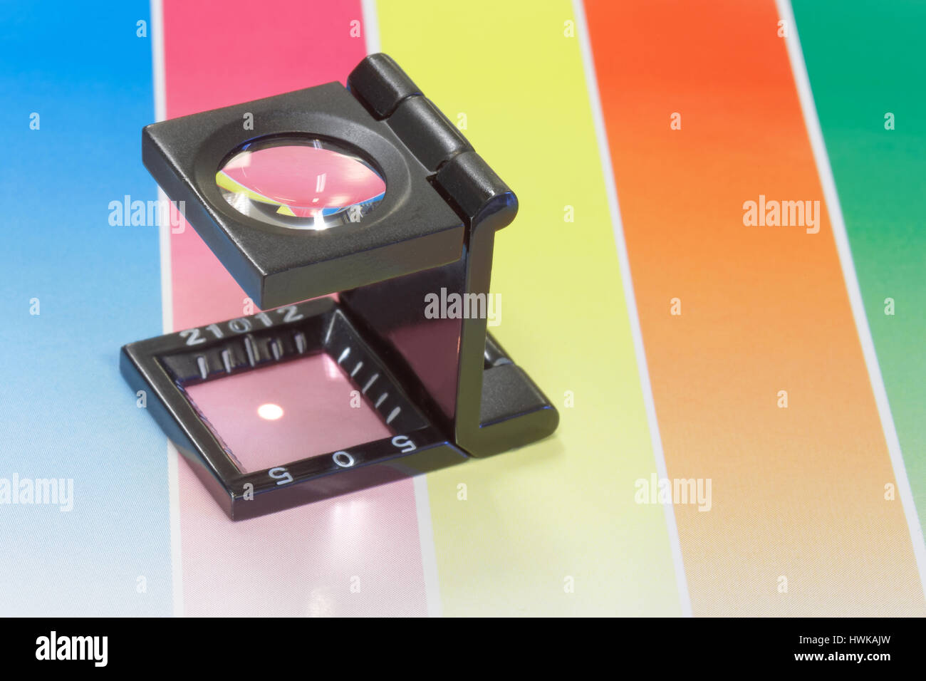 Magnifier or printer's loupe sits on a colorful CMYC test sheet in a ...